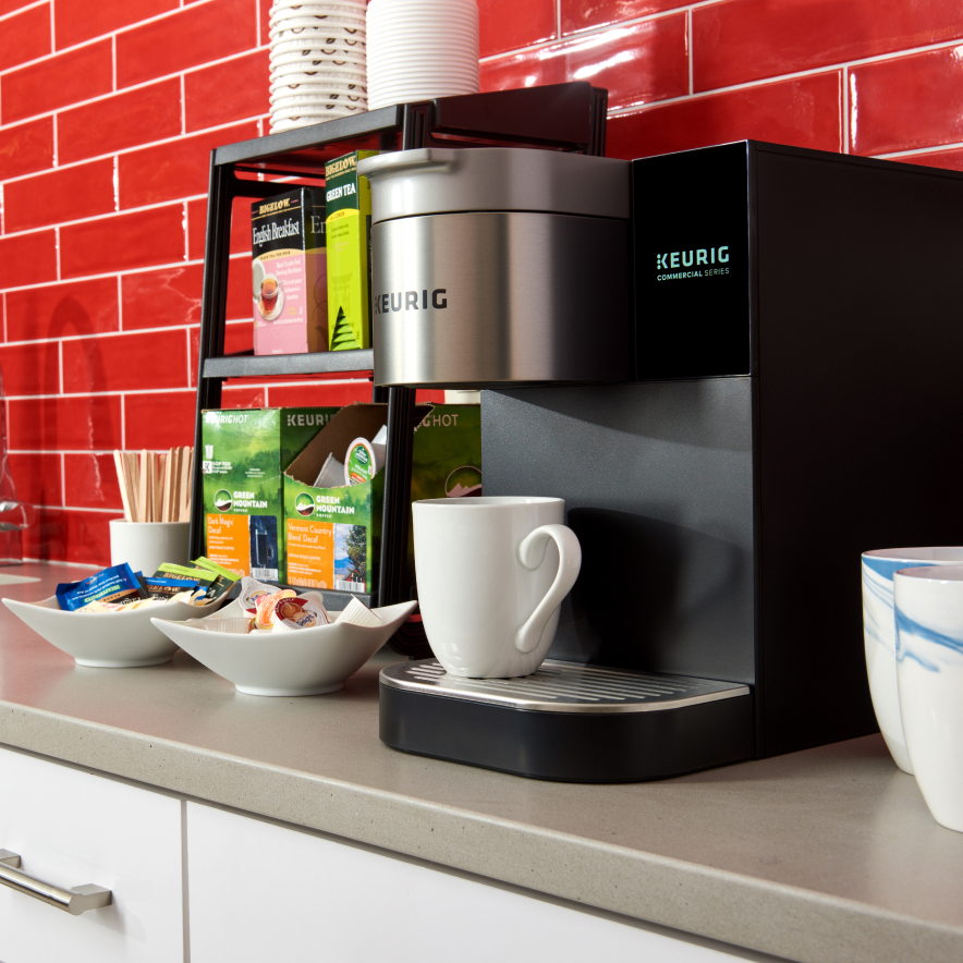 Lifestyle image of the Quench 171 Keurig coffee brewer on a countertop with break room supplies