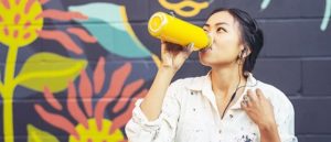A woman drinking out of a reusable water bottle