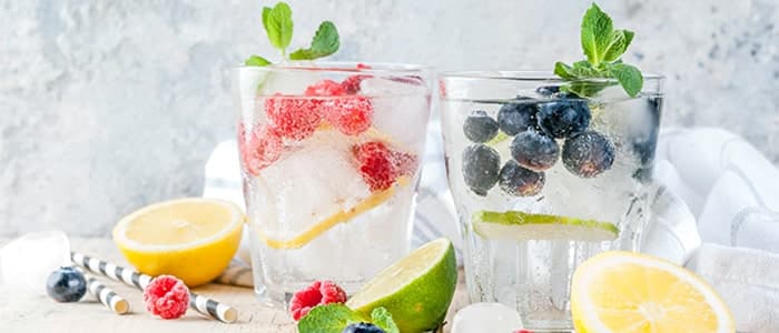 Two glasses of sparkling water with fruit in them