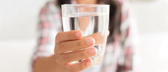 A woman holding a glass of still water