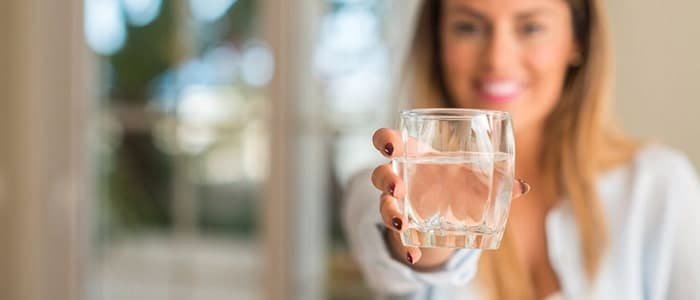 A woman holding out a glass of still water