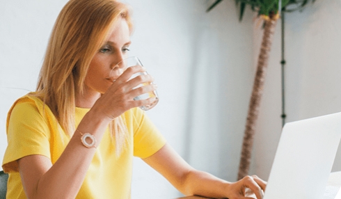 A woman drinking a glass of water in her office