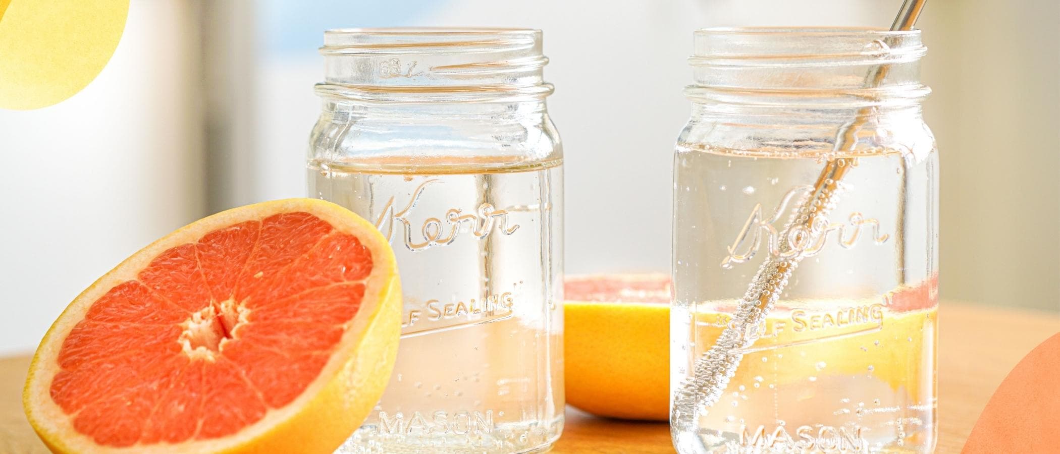 Grapefruit next to sparkling water in mason jar