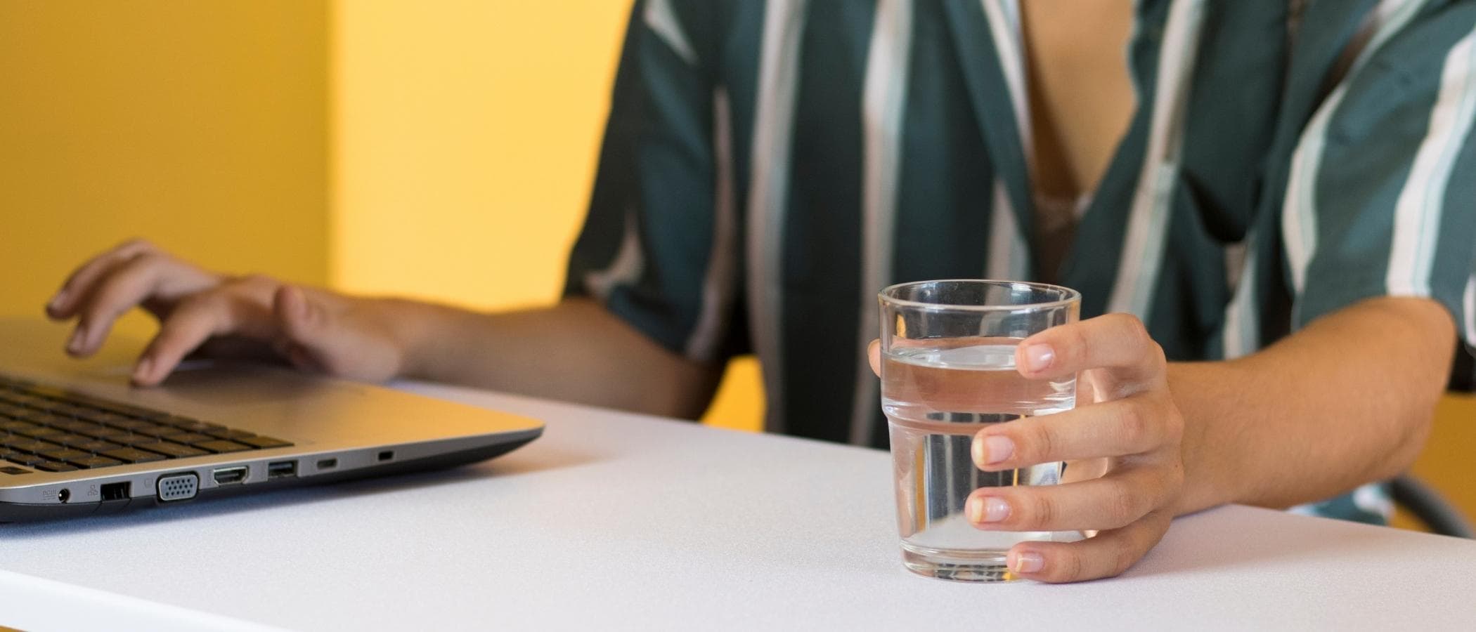 Glass of water on desk near laptop