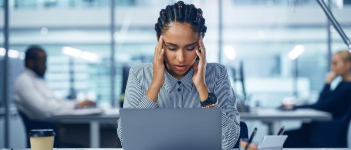 Young woman holding her head in pain at computer