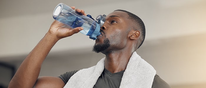 man drinking water in the gym for blog hero image