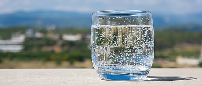 glass filled with sparkling water with natural background