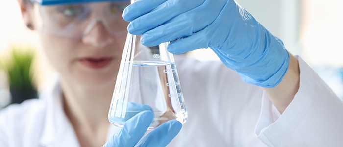 Woman in lab coat looking at water in a beaker