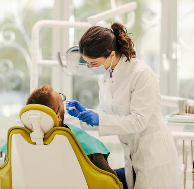 Female dentist examining male patients mouth