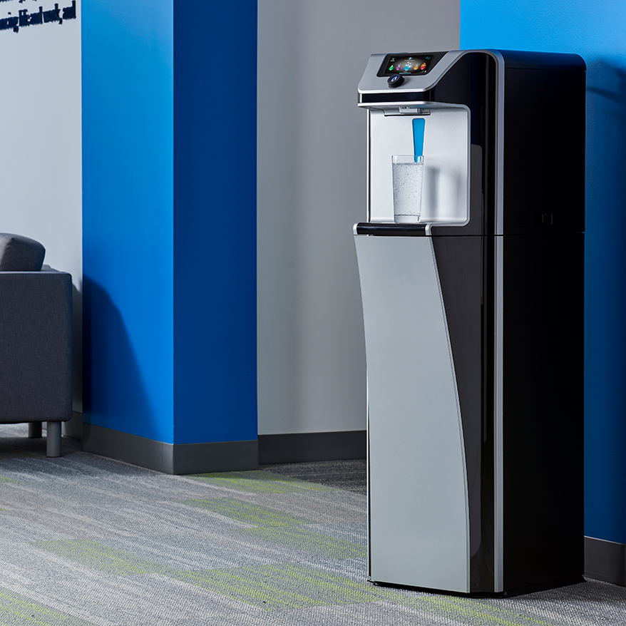 Quench Q9 freestanding water dispenser with a glass of water beneath it