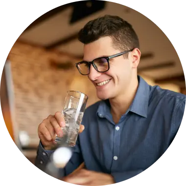 man with glasses drinking ice water at desk at work